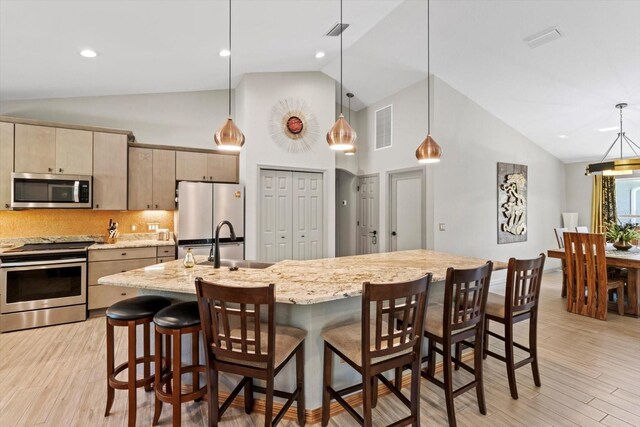 kitchen with high vaulted ceiling, stainless steel appliances, light wood-style flooring, and visible vents