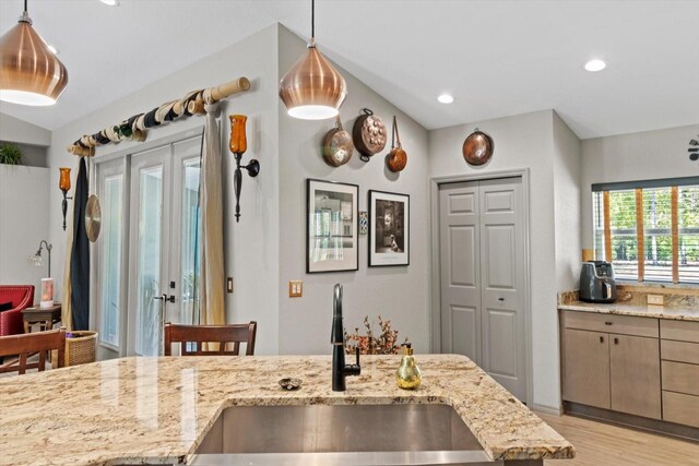 kitchen with pendant lighting, light stone countertops, a sink, light wood-style floors, and recessed lighting