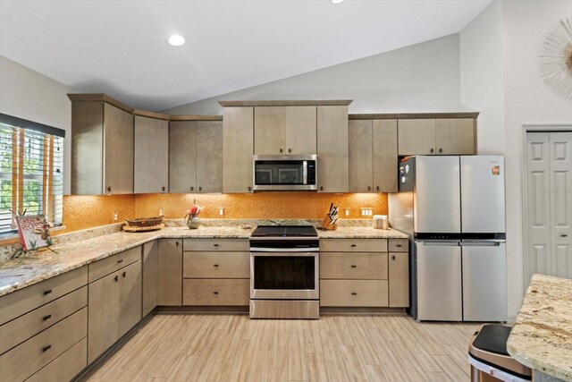 kitchen with light brown cabinets, light wood-style flooring, stainless steel appliances, backsplash, and vaulted ceiling