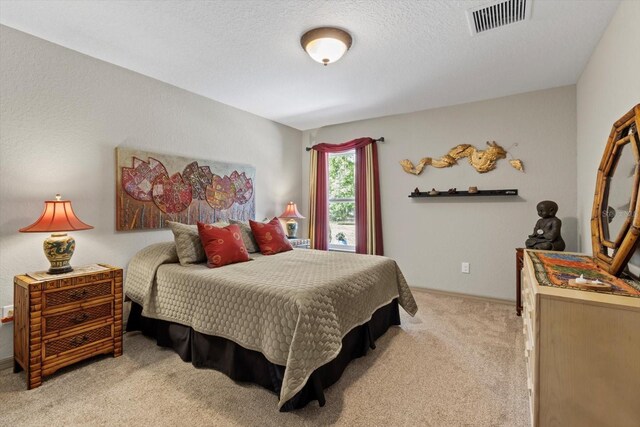 bedroom with light carpet, a textured ceiling, and visible vents