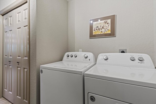 clothes washing area featuring washing machine and clothes dryer, laundry area, and a textured wall