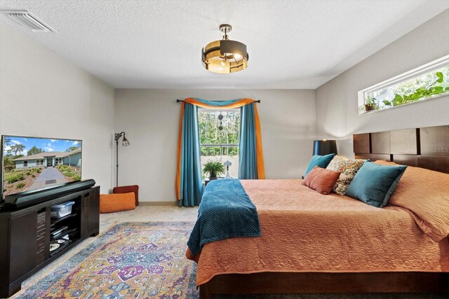 bedroom featuring visible vents, a textured ceiling, carpet floors, and baseboards