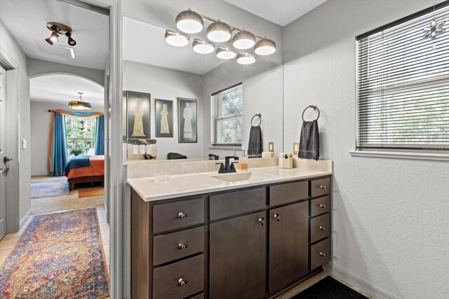 bathroom with ensuite bathroom, a textured wall, and vanity