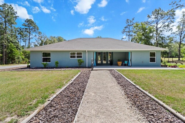 view of front of house with french doors, a shingled roof, a front yard, and stucco siding