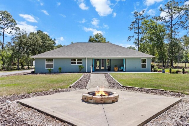rear view of property with a lawn, an outdoor fire pit, french doors, and a patio