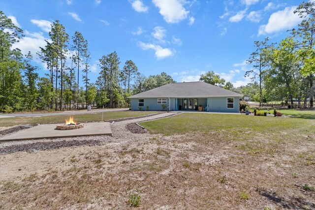back of house with a lawn and a fire pit