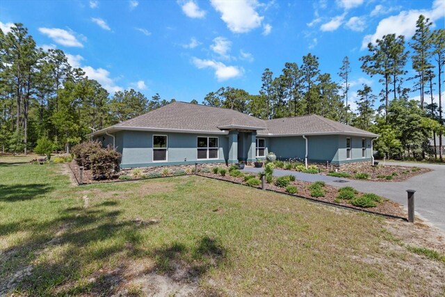 view of front of home featuring stucco siding, stone siding, and a front yard