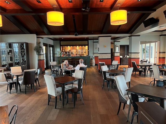dining space featuring vaulted ceiling with beams, wood finished floors, and wooden ceiling