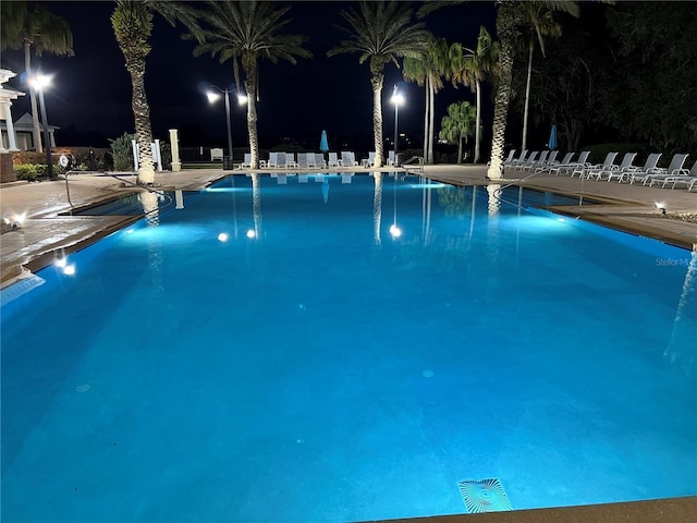 pool at night featuring a community pool