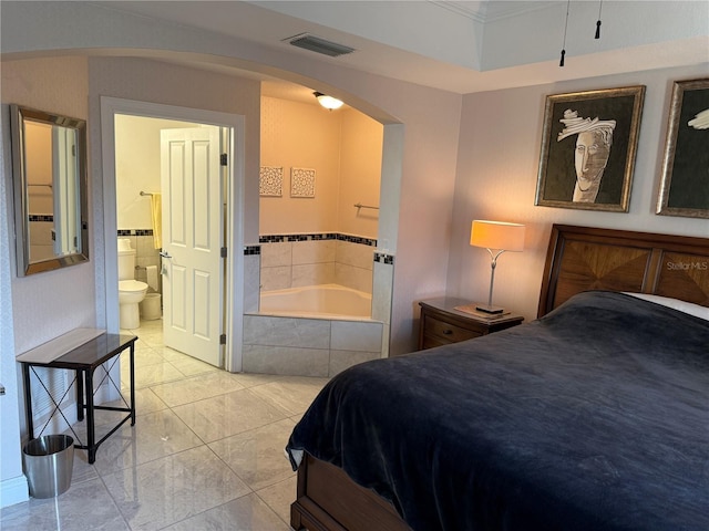 bedroom with visible vents, arched walkways, and connected bathroom