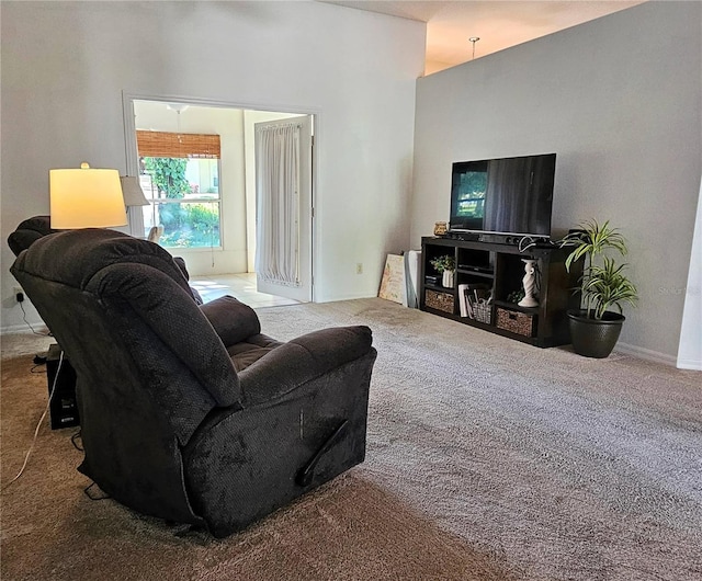 living area featuring carpet floors, baseboards, and a high ceiling