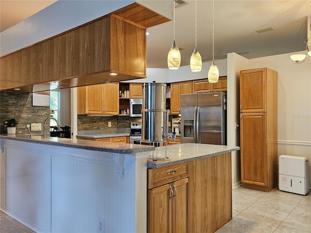 kitchen featuring brown cabinetry, decorative backsplash, appliances with stainless steel finishes, and a peninsula