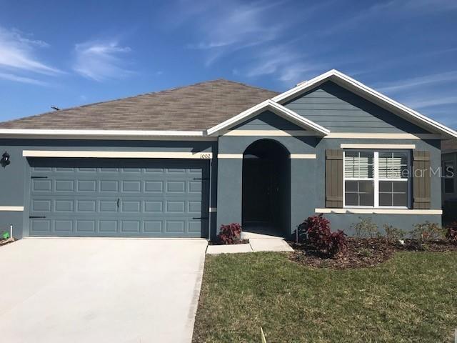 ranch-style house with an attached garage, a front lawn, driveway, and stucco siding