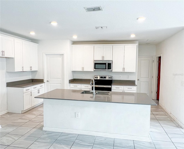 547 Jett Ln, Davenport, FL 33837 - kitchen with stainless steel appliances, recessed lighting, a kitchen island with sink, white cabinets, and dark countertops