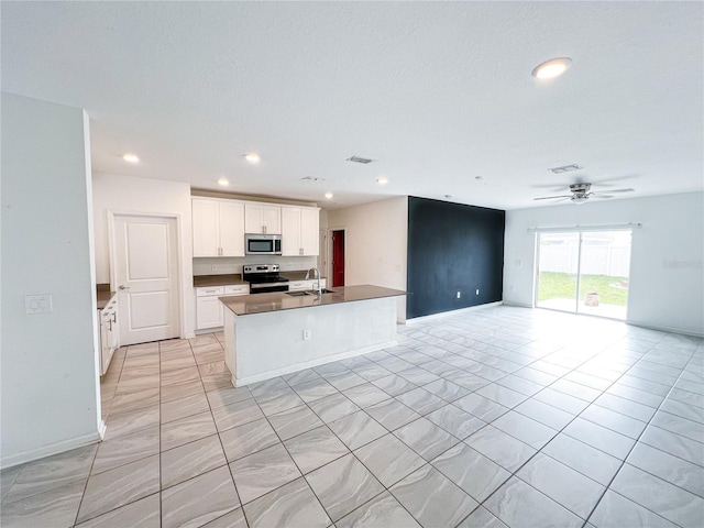 547 Jett Ln, Davenport, FL 33837 - kitchen with appliances with stainless steel finishes, open floor plan, a center island with sink, white cabinetry, and dark countertops