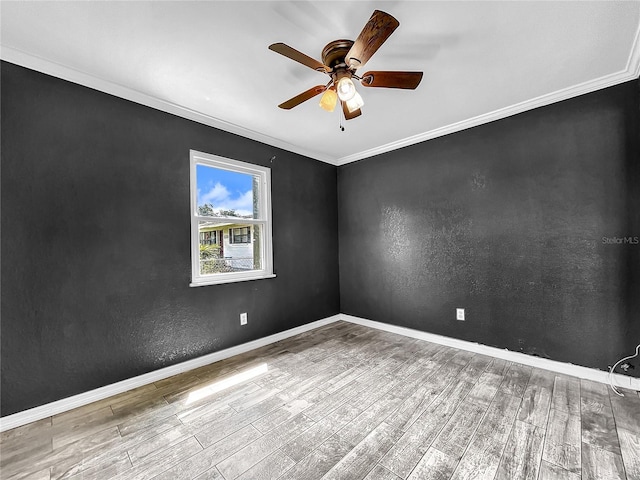 empty room with baseboards, ceiling fan, ornamental molding, and wood finished floors