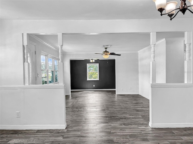 empty room featuring crown molding, baseboards, a wealth of natural light, and ceiling fan with notable chandelier
