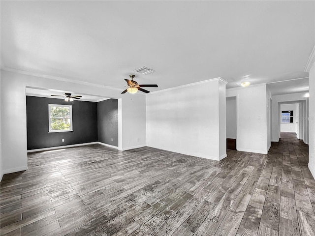 empty room with crown molding, a ceiling fan, dark wood-style flooring, and visible vents