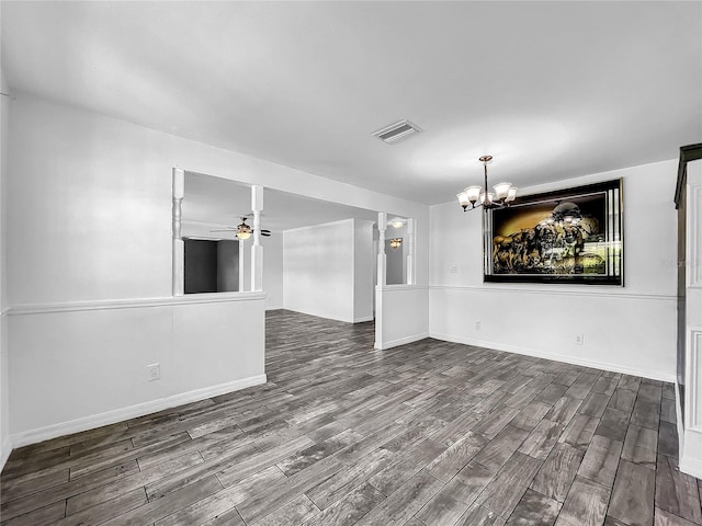 empty room featuring visible vents, dark wood finished floors, ceiling fan with notable chandelier, and baseboards