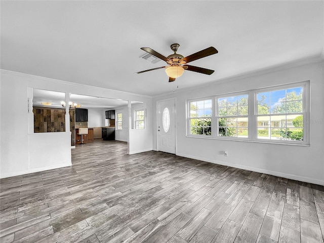 unfurnished living room featuring baseboards, ceiling fan with notable chandelier, and wood finished floors