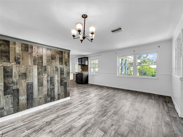 spare room with visible vents, baseboards, wood finished floors, and an inviting chandelier