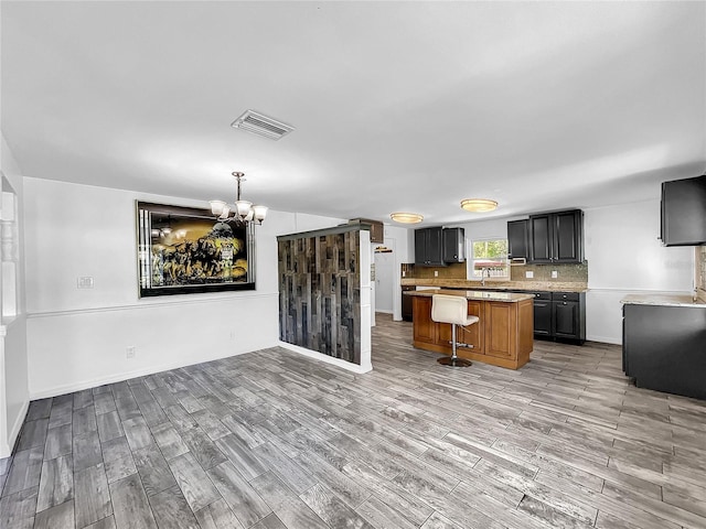 kitchen with light countertops, a chandelier, decorative backsplash, and light wood-style floors