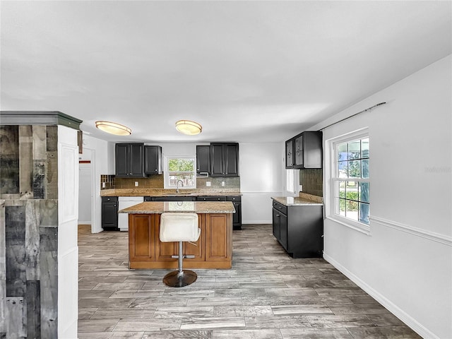 kitchen featuring light wood-style floors, decorative backsplash, baseboards, and a kitchen island