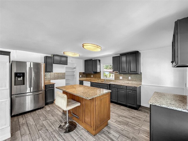 kitchen featuring stainless steel refrigerator with ice dispenser, white dishwasher, backsplash, and wood finish floors