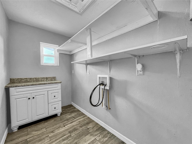 clothes washing area featuring baseboards, laundry area, wood finished floors, and hookup for a washing machine