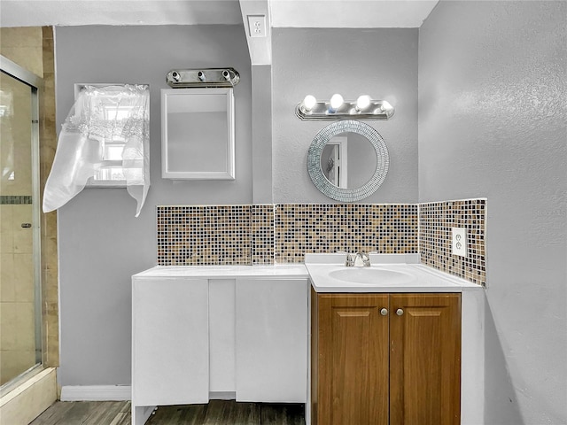 bathroom featuring vanity, tasteful backsplash, wood finished floors, and a stall shower