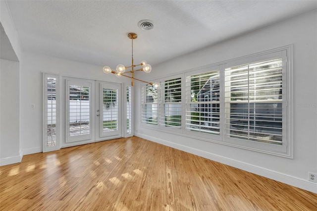 1231 Glastonberry Rd, Maitland, FL 32751 - unfurnished dining area with a textured ceiling, visible vents, baseboards, a chandelier, and light wood-style flooring