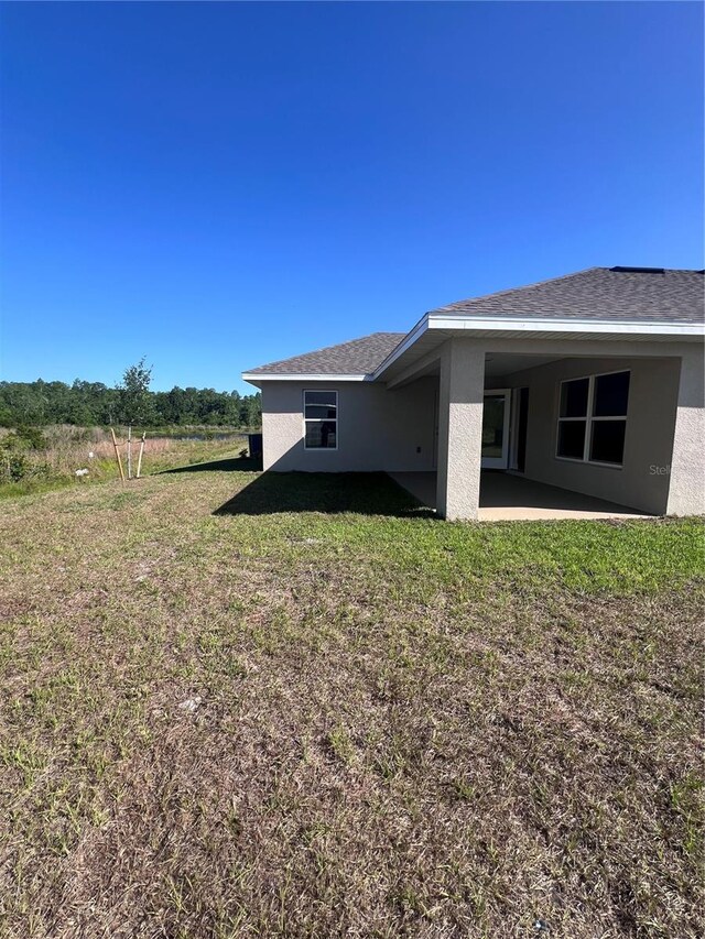 4264 Sagefield Dr, Saint Cloud, FL 34773 - view of side of property featuring a lawn, a patio area, and stucco siding