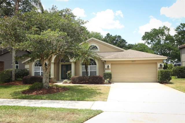 view of front of house with a garage, a front lawn, stucco siding, and driveway