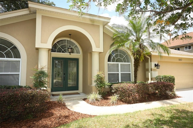 view of exterior entry with a garage, stucco siding, and french doors