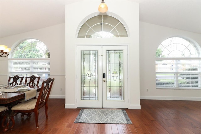 foyer entrance with baseboards, a notable chandelier, wood finished floors, and lofted ceiling