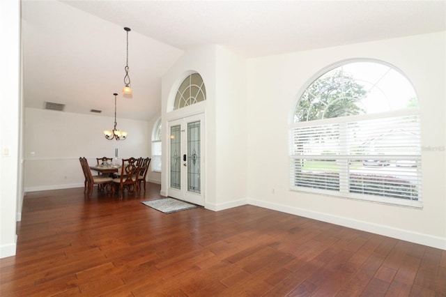 dining space featuring a chandelier, visible vents, wood finished floors, baseboards, and lofted ceiling