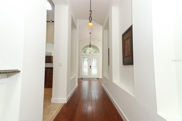 hallway with baseboards, french doors, dark wood finished floors, and a towering ceiling