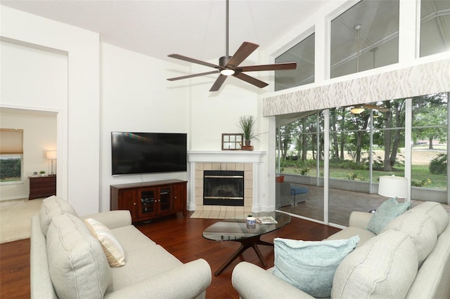 living area with ceiling fan, wood finished floors, high vaulted ceiling, and a tile fireplace
