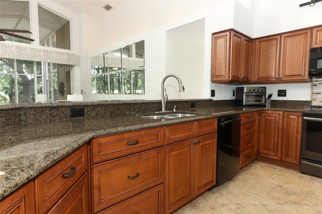 kitchen featuring visible vents, brown cabinets, a sink, dark stone countertops, and black appliances