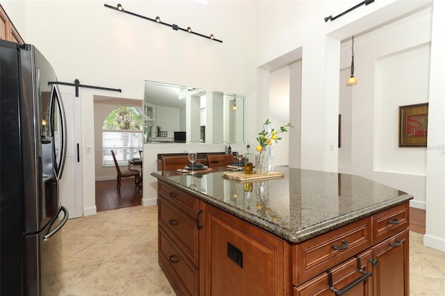 kitchen featuring baseboards, freestanding refrigerator, dark stone counters, and a barn door