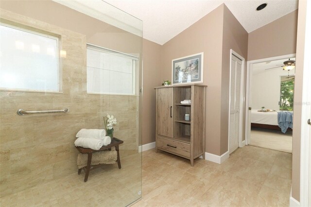 ensuite bathroom featuring tile patterned flooring, walk in shower, lofted ceiling, and ensuite bath