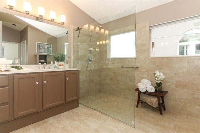 bathroom featuring vanity, tile patterned floors, walk in shower, and lofted ceiling