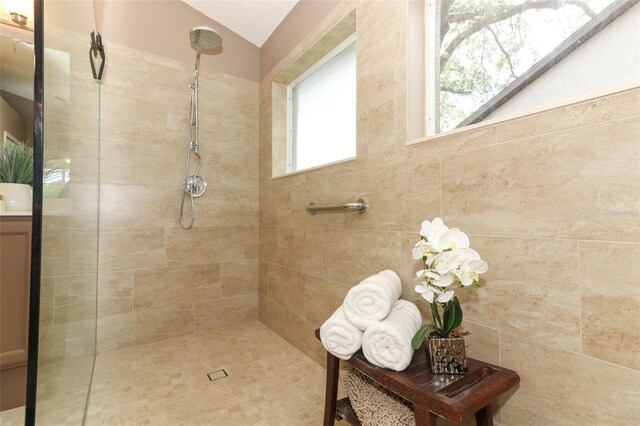 bathroom with vaulted ceiling and tiled shower