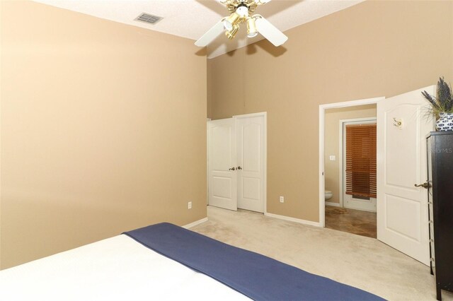 unfurnished bedroom with visible vents, a towering ceiling, baseboards, light colored carpet, and a ceiling fan