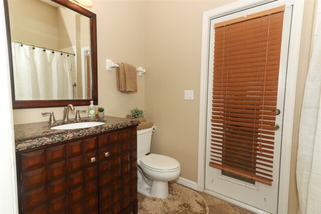 bathroom featuring toilet, tile patterned floors, baseboards, and vanity