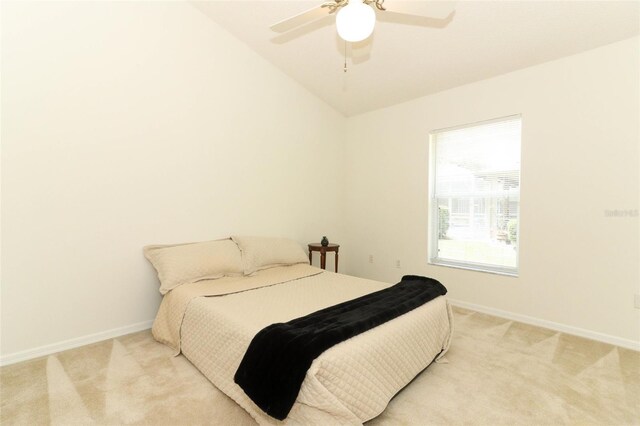 bedroom featuring light colored carpet, baseboards, and vaulted ceiling