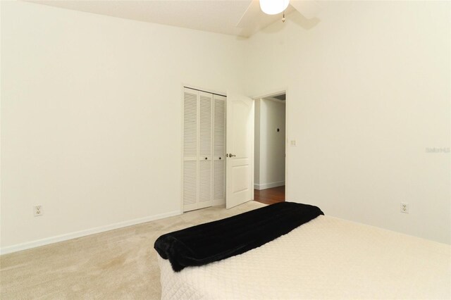 carpeted bedroom with vaulted ceiling, baseboards, ceiling fan, and a closet