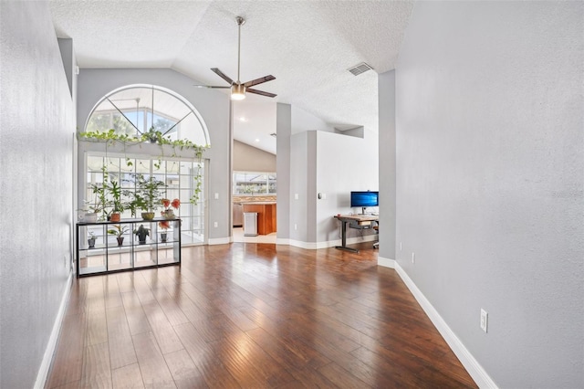 unfurnished living room with visible vents, lofted ceiling, wood finished floors, baseboards, and ceiling fan