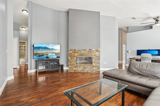 living area with visible vents, wood finished floors, a fireplace, a textured ceiling, and a ceiling fan