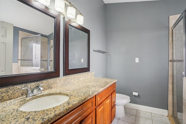 bathroom featuring tile patterned flooring, vanity, toilet, baseboards, and a shower stall